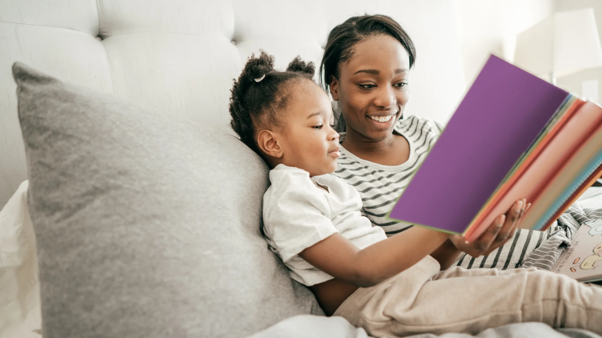 Child sits with their mother reading a book