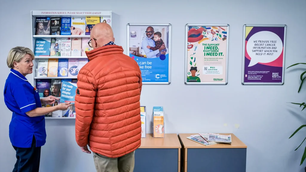 Two people in a GP reception looking at the leaflets